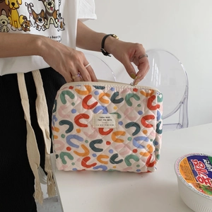 Detailed shot of floral quilted cotton makeup bag with zip closure held by hand