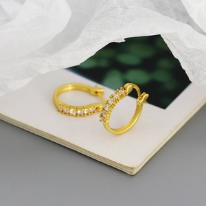 Macro view of gold hoop earrings with sparkling cubic zirconia on a white book page