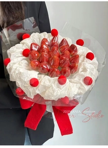Close-up of strawberry bouquet with plush red pom-poms and elegant velvet ribbon bow
