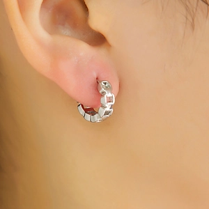 Vue macro d'une boucle d'oreille créole géométrique argentée portée à l'oreille