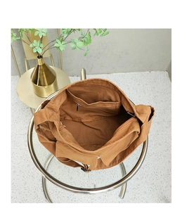 Detail view of the brown canvas messenger bag interior with a zipper pocket for storage