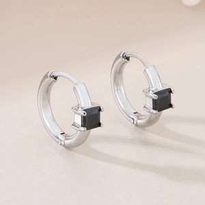 Detail of silver hoop earrings featuring square-cut black gemstone and four-prong setting