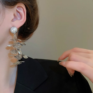 Detailed close-up of tiered silver leaf tassels and large white pearl earrings