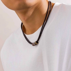 Close-up of minimalist leather knotted necklace with metallic ring beads on male model