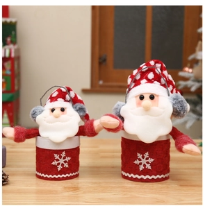 Close-up of plush Santa Claus candy jars with red felt and snowflake detail on wood table