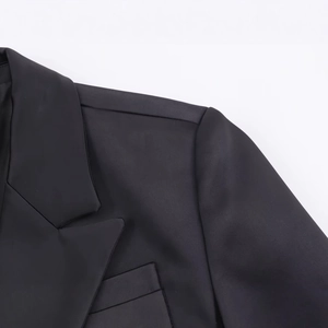 Close-up of black herringbone wool blazer showing shoulder detail and tailored lapel