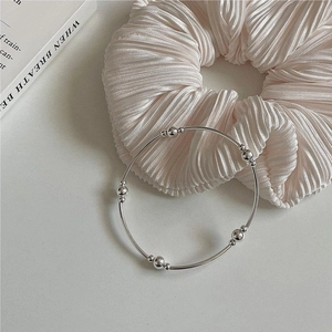 Close-up of minimalist S925 sterling silver beaded bangle on soft beige fabric