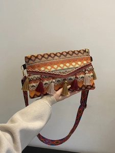 Detail of bohemian woven crossbody bag with colorful tassels and geometric wide strap