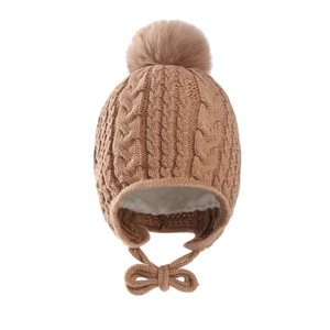 Close-up of cable knit baby hat featuring plush faux fur pom and warm fleece lining