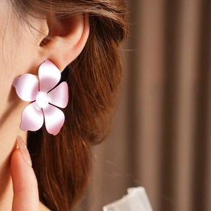 Détail de boucles d'oreilles fleur rose mat avec pétales dégradés sur l'oreille