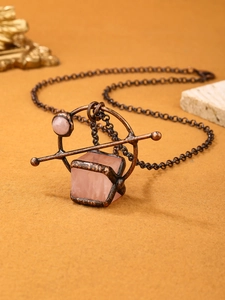 Macro shot of vintage rose quartz cube pendant with antique bronze frame on long chain