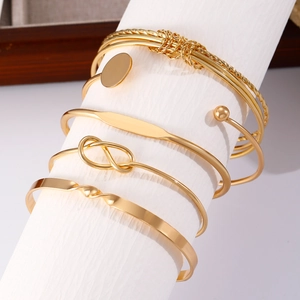Vijfdelige gouden armbandset met knoop, platte twist en ronde schijfvormige bedels