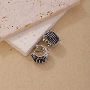 Détail de boucles d'oreilles argentées serties de zircons noirs sur marbre gris