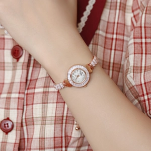 Close-up of rose gold watch with rectangular crystals on a model's wrist