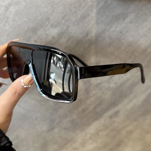 Close-up of black square frame sunglasses with shiny finish held in hand