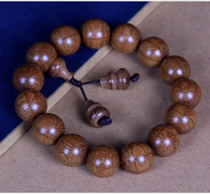Macro detail of natural Wutai wood beads with visible grain and a gourd-shaped charm