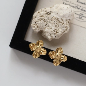 Macro shot of gold-plated liquid metal flower earrings with detailed textured stamens