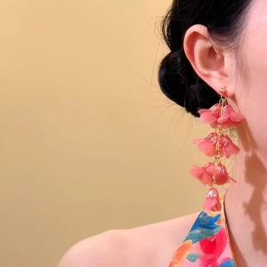 Close-up of elegant pink lily-of-the-valley floral tassel earrings worn by a model