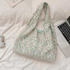 Detailed close-up of light green canvas shoulder bag with vintage white lace overlay