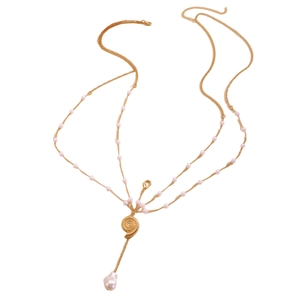 Detail of layered gold body chain with pearl accents and spiral shell pendant
