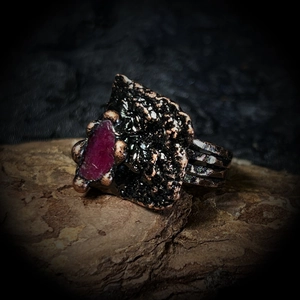 Détail d'une bague ajustable vintage avec pierre brute rouge et texture métallique sombre