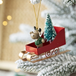 Nordic Christmas reindeer ornament in red iron sleigh with a snowy pine tree