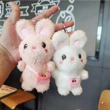 Close-up of pink and white plush astronaut bunny keychains held in hand for backpack decor