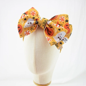 Detail of orange waffle fabric baby headband with ghost and pumpkin Halloween prints