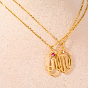 Detail of two gold zodiac necklaces featuring hollowed symbols and pink gemstones