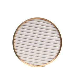 Detail view of round gold metal jewelry tray with cream velvet slots for ring display
