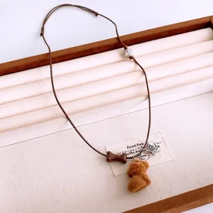 Cute plush puppy pendant necklace with bone and silver star on a brown adjustable rope