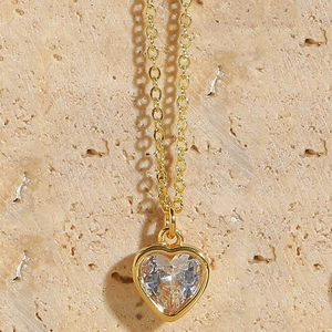 Macro shot of gold heart pendant necklace featuring a clear faceted zircon gemstone