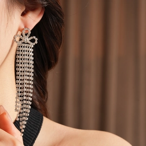 Primo piano di orecchini a nappa in argento scintillante con design a fiocco su una modella