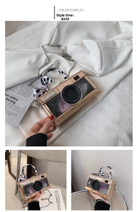 Close-up of rose gold camera-shaped handbag with rhinestones and polka dot silk scarf