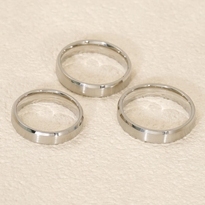 Detailed view of three polished silver titanium rings with beveled edges on a textured surface