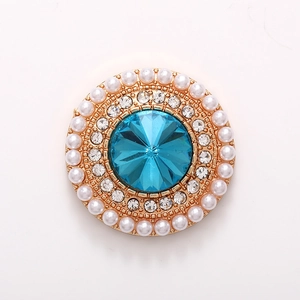 Macro detail of round light blue crystal charm with white pearls and gold alloy base