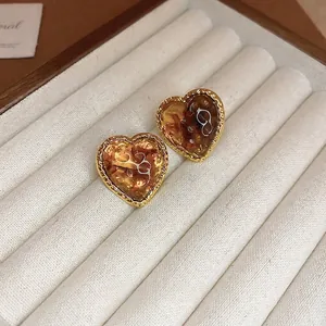 Elegant gold-edged amber heart stud earrings with vintage wavy texture on velvet
