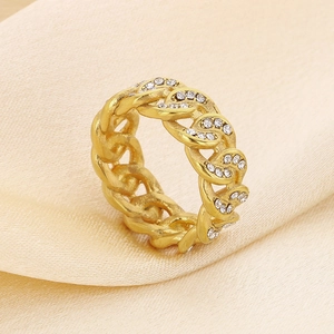 Detailed view of a gold chain ring with sparkling white rhinestones on silk fabric
