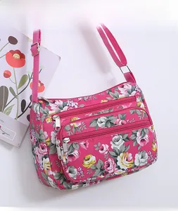 Close-up of floral print shoulder bag with multi-zipper pockets and adjustable strap