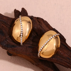 Macro shot of 18K gold plated oval earrings with vertical white zircon stones on wood