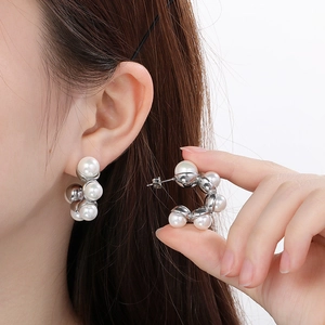 Gros plan de boucles d'oreilles en C en acier inoxydable avec de grandes perles blanches
