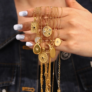 Gold stainless steel star and moon pendant necklaces featuring zircon inlays on a hand