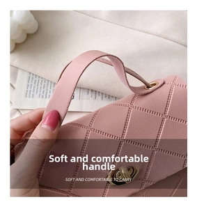 Close-up of pink quilted leather handbag featuring a soft handle and gold metal twist lock