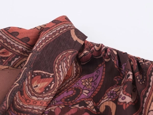 Detail of bohemian paisley print chiffon dress with intricate tie-neck and vintage patterns