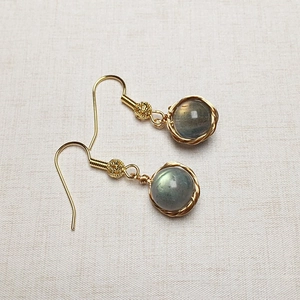 Détail macro de boucles d'oreilles en or 14K avec une pierre précieuse labradorite ronde