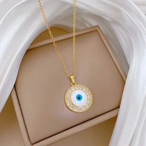 Close-up of a golden titanium steel necklace with a blue evil eye pendant and zircon crystals