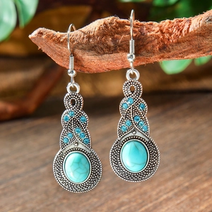 Macro view of vintage silver drop earrings with blue turquoise stones on a branch
