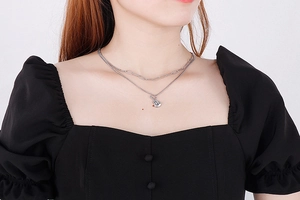 Detail of layered silver music necklace with guitar pendant on paperclip chain