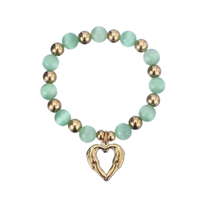 Detail of beaded bracelet with mint green cat eye stones and golden heart charm