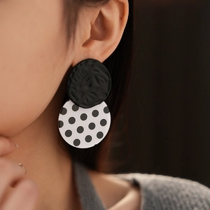 Close-up of black and white polka dot acrylic stud earrings on model for a chic look